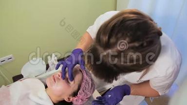 美容师在女人的脸上涂了一层舒缓霜。中胚层治疗后<strong>皮肤发红</strong>、发炎。辉光